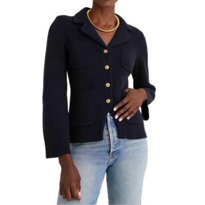 A woman wearing a navy cardigan with gold buttons and light blue jeans