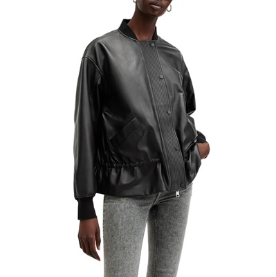 A woman wearing gray pants and black leather bomber jacket