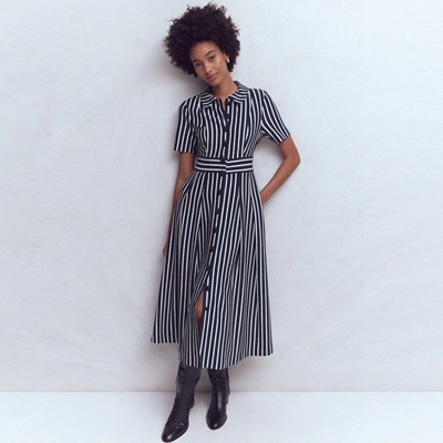 A woman wearing a navy-and-ivory striped shirtdress and black tall boots