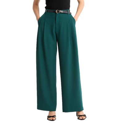 A woman wearing a black top, belt, dark green pants, and black heels