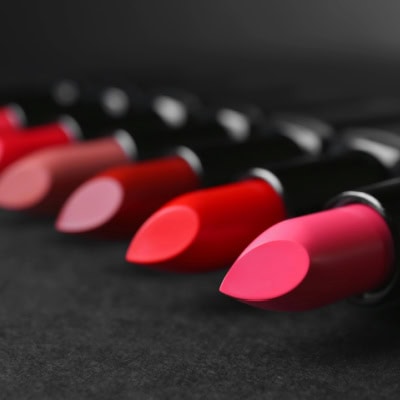 tubes of lipstick laying on a dark surface