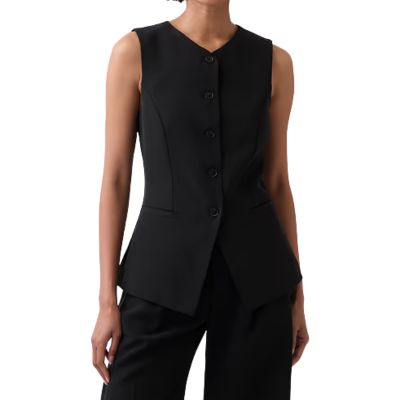 A woman wearing a long black vest and black pants