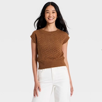 A woman wearing a short-sleeve brown sweater and white pants