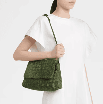 woman wears white dress with weirdly large sleeves and a green suede leather bag that is gorgeous although probably leaving marks on her dress