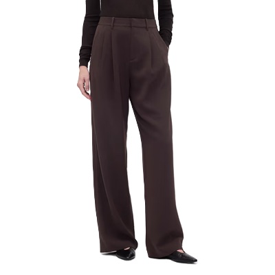 A woman wearing black flats, a black top, and dark brown pants 