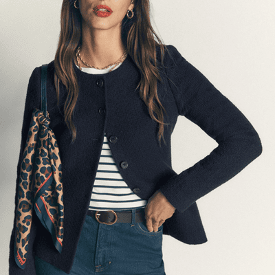 woman wears collarless cutaway hem blzer with stripey t-shirt beneath it