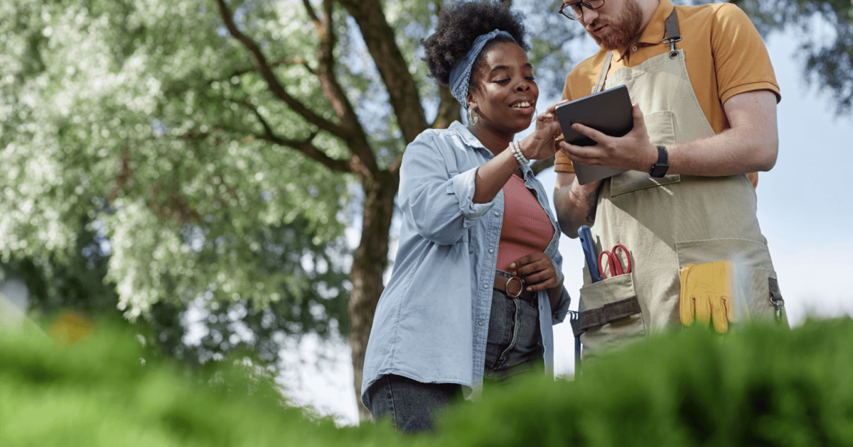 Polished Black woman reviews a tablet with a landscaping professional