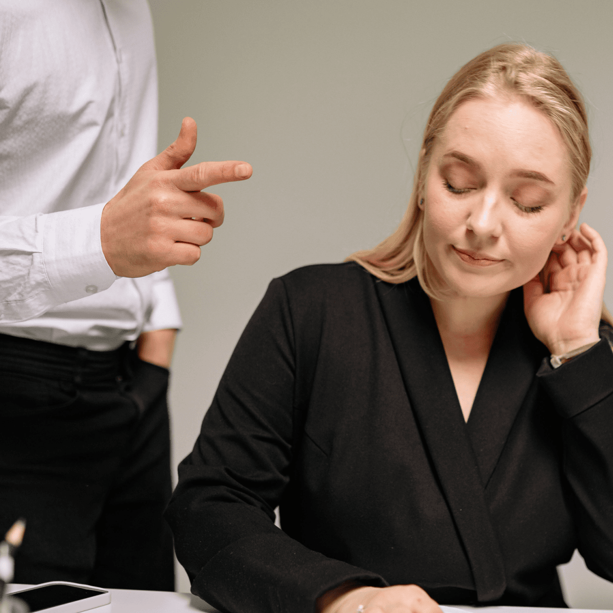 Professional woman has a long-suffering expression while a male colleague gestures beside her.