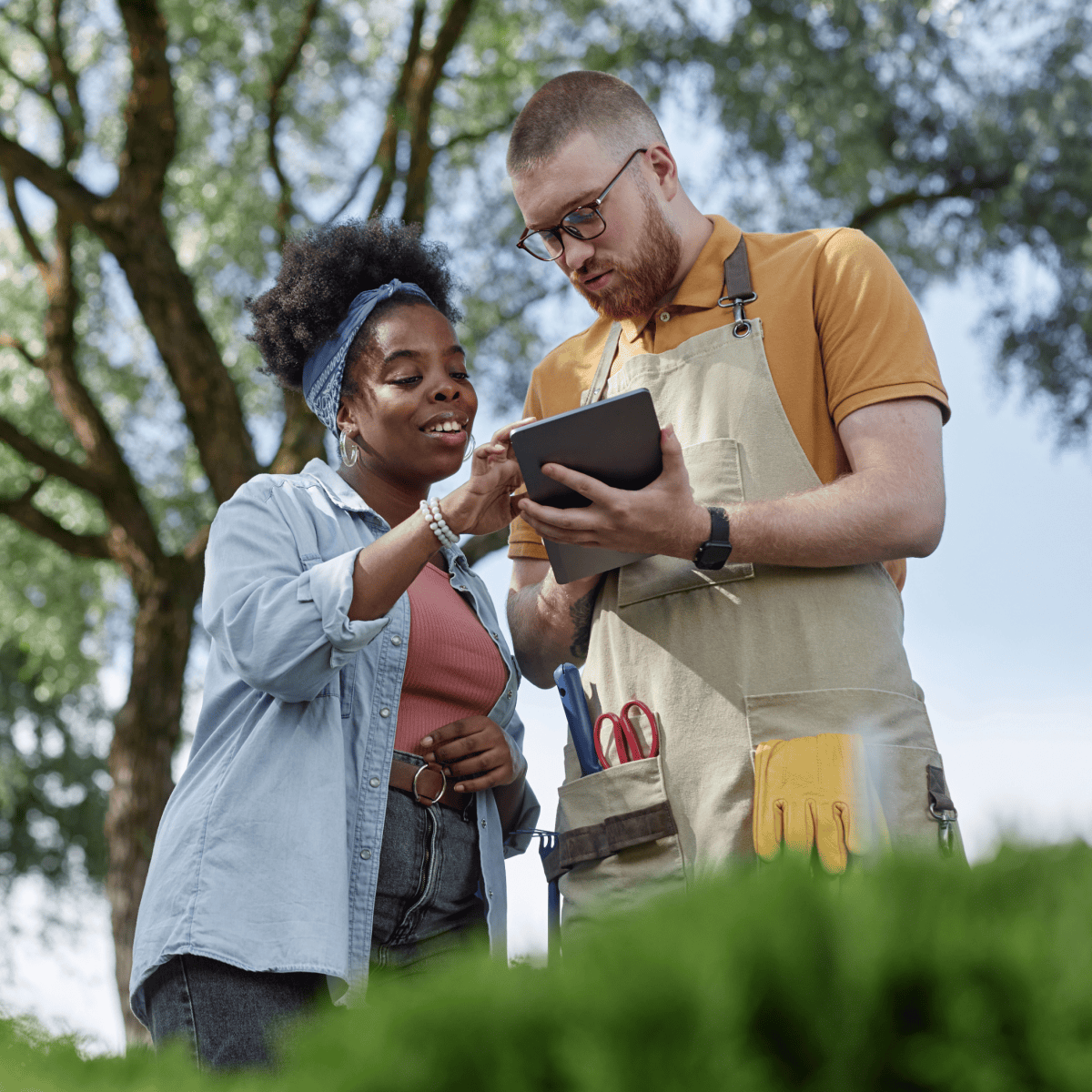 Polished Black woman reviews a tablet with a landscaping professional
