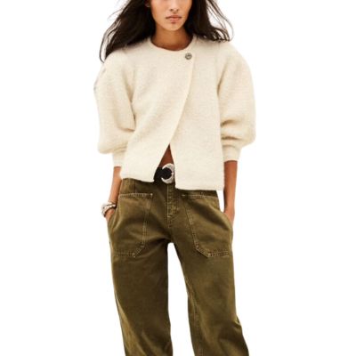 A woman wearing a cream cardigan and brown pants