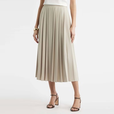 A woman wearing a tan midi skirt, white top, and strappy brown heels