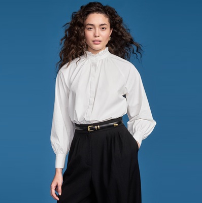 A woman wearing a long-sleeved white blouse, black pants, and black belt