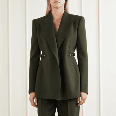 woman wears dark green Hearst suit with chain detail at waist