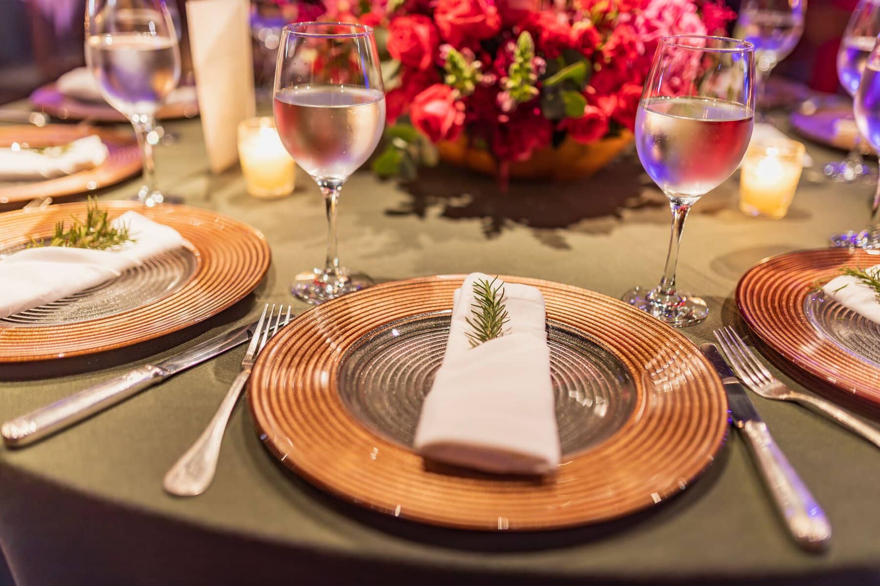 Luxurious table setting with glasses of water and floral centerpiece at a beautifully arranged dining table.