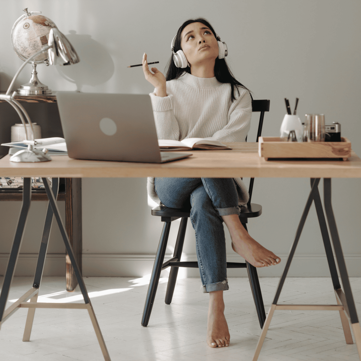 Woman wearing headphones, leaning back at her desk and looking upward while taking a break from work.