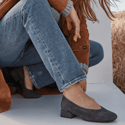 woman in jeans wears Vionic Petra Flat in gray; she is crouching on the floor